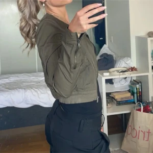 Olivgrön bomberjacka med dragkedja - Snygg olivgrön bomberjacka med dragkedja framtill och ribbade muddar. Jackan har en klassisk bomberpassform och detaljerade sömmar på ärmarna. Perfekt för dig som vill ha en stilren och trendig look. Super nu till sommaren!!! Så söt , vet inte märket men köpte secondhand 💓💓