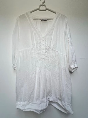 Vit blus - Super fin blus/tunika ifrån Cappuccini i storlek 42🌺                                                                                - V-ringning - 5 st knappar vid brösten - Fina brodyr detaljer på framsida och längs armarna - Tre kvartsärmar