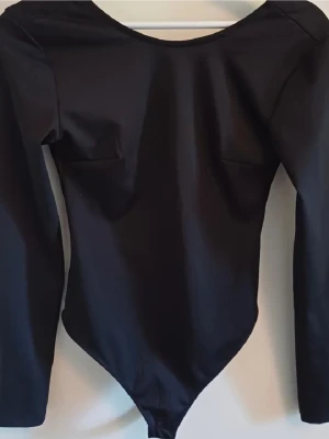 Svart långärmad body - Säljer en svart långärmad body med rundad hals och djup rygg. Perfekt för sommaren eller fest ❤️