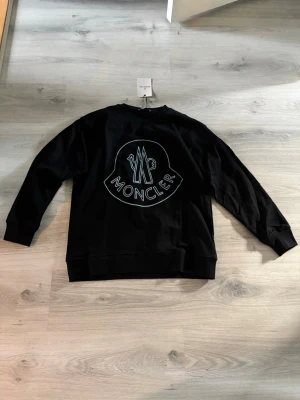Moncler sweatshirt med blått tryck  - Oanvänd moncler sweatshirt, inte använd och nyskick då den satt konstigt på mig, kan tänka mig gå ner något i pris 
