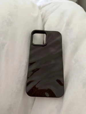 Brunt  glansigt mobilskal  - Brunt  mobilskal med glansig finish och slimmad design. Skalets material är hårdplast och det har en stor öppning för kameran. Passar perfekt för dig som vill ha ett stilrent och enkelt skydd till mobilen. iPhone 12, 13