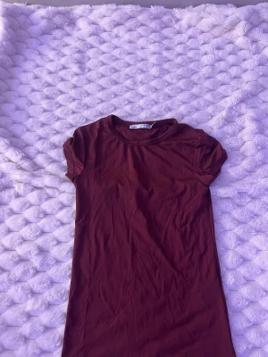 Vinröd kortärmad klänning - En enkel och stilren vinröd klänning med korta ärmar och rund halsringning. Klänningen har en rak passform och är tillverkad i mjukt bomullstyg, perfekt för en avslappnad look.