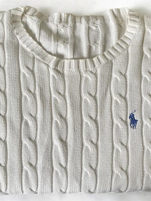 Vit kabelstickad tröja Polo Ralph Lauren - Kabelstickad vit tröja från Polo Ralph Lauren med rund halsringning och blå broderad logga på bröstet. Tröjan har långa ärmar och ribbade muddar vid ärmslut och nederkant. Perfekt för en klassisk och stilren look.