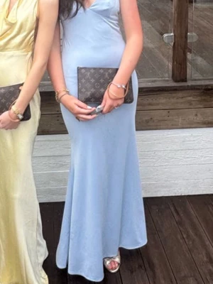 Ljusblå långklänning med v-ringning - Fin balklänning avänd endast en gång och är i toppen skick. Den är uppsydd lite i längden som syns på bilden. Köpt från Nelly förra året!