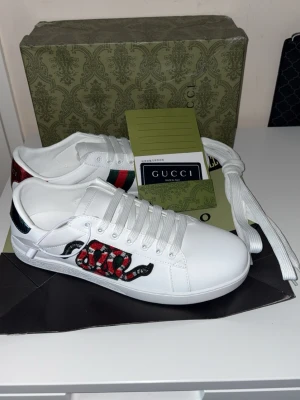 Gucci vita sneakers med orm - Vita Gucci Ace sneakers med en slående ormbroderi. Levereras med originalkartong och äkthetsintyg.  ⭐️ Skick: 9/10 🎨 Färg: Vit 📦 Snabb och noggrann leverans