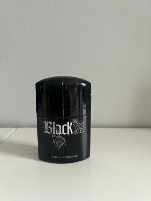 Paco Rabanne Black XS parfym - Black XS parfym från Paco Rabanne i en cool, svart flaska med silverfärgad text och rosdetalj. Flaskan har en modern, rundad form och är tillverkad i glas och plast. Perfekt för dig som gillar unika och stilrena dofter. Nästan helt ny som synes på sista bilden