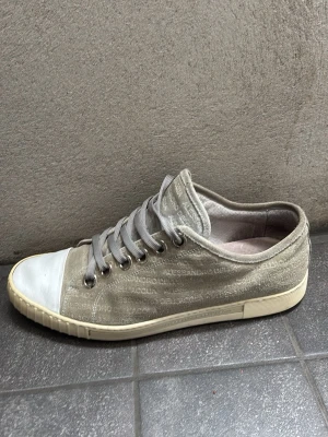 Sneakers från Italien - Snygga gråa sneakers från Italien. Snören och vit patch där fram. Perfekta nu inför vår och sommar. I sttorlek 44 och fint skick! Tveka inte på att höra av er vid funderingar.