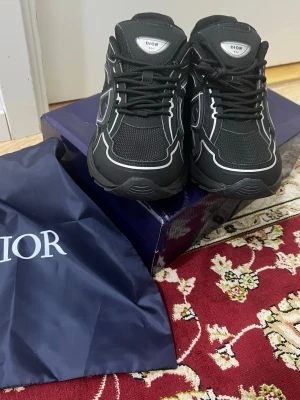 D skorna  - Storlek 43 Snygga svarta  sneakers med vita kontrastdetaljer och meshpaneler för extra andningsförmåga. Skorna har en chunky sula och klassisk snörning. Märkeslogga syns på plösen och sidan. Perfekta för dig som vill ha en exklusiv och modern look.