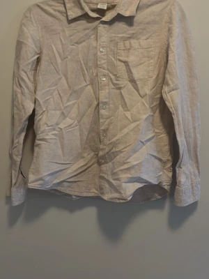 Beige linneskjorta med bröstficka - Stilren beige skjorta i linne med klassisk krage och knappstängning framtill. Skjortan har en bröstficka och långa ärmar med manschett. Perfekt för en avslappnad men ändå snygg look.