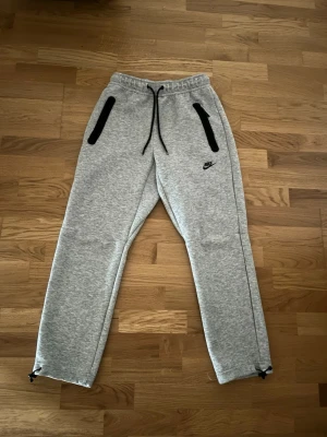 Grå Nike Tech byxor - Säljer ett par gråa Nike Tech byxor, Dom är helt nya, aldrig använt! 