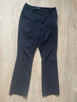 Svarta kostymbyxor från BikBok - Svarta kostymbyxor från BikBok med klassisk passform och raka ben. Byxorna har hällor för bälte och diskret dragkedja framtill. Perfekta för en stilren look och passar till många olika outfits.