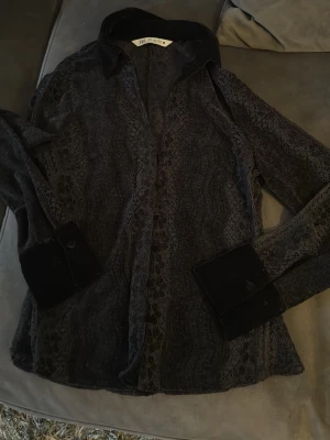 Svart spetsblus från ZARA - Snygg svart skjorta från ZARA med transparent spetsdetaljer längs ärmar och framstycke. Skjortan har klassisk krage och breda manschetter i sammet för en extra lyxig känsla. Storlek S! 