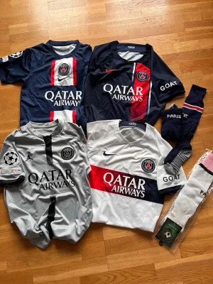 PSG matchtröjor och strumpor  - Säljer ett paket med Paris Saint-Germain matchtröjor från Nike i olika färger: marinblå, vit och grå, med Qatar Airways-tryck och klubbmärke. Inkluderar även ett par PSG-strumpor.  Alla tröjor är i funktionsmaterial, perfekta för fotbollsträning eller match. Endast använda ett fåtal ggr.  600 kr för alla eller 180 kr/styck. 