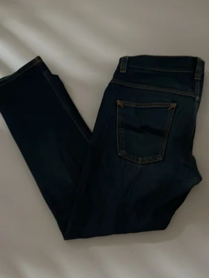 Mörkblå jeans från Nudie Jeans - Säljer ett par mörkblå jeans från Nudie. Storleken är 32:32. Jag säljer dem då jag är sugen på något nytt. Nypris:1200 Mitt pris: 349. Hör av dig om du har eventuella frågor!