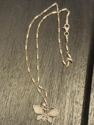 925 silver halsband med fjärilshänge - Snyggt halsband i äkta 925 silver med ett detaljerat fjärilshänge. Kedjan har små cylinderformade länkar och hänget är dekorerat med glittrande pärlor som ger extra bling. Perfekt accessoar för att lyfta din outfit.
