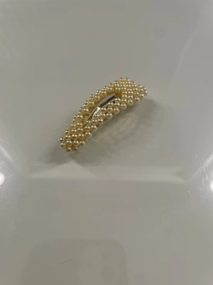 Hårspänne - Ett hårspänne med en pastelli gul färg 