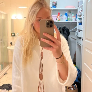 Vit långärmad topp med knyt - Vit långärmad topp med tre knyt framtill. Från Gina Tricot, strl 38