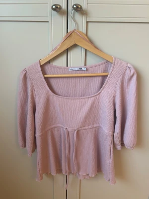 Ljusrosa ribbad topp från lager 157 - Supersöt ljusrosa topp från lager 157 med ribbad struktur och knyt i midjan. Toppen har trekvartsärm och en fyrkantig ringning som ger en trendig vibe. Perfekt att styla med jeans eller kjol för en chill look.