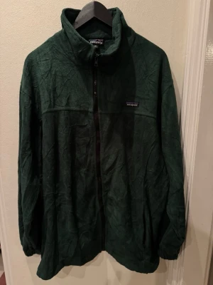 Patagonia full-zip fleecejacka mörkgrön stl XXL herr - Patagonia full-zip i mjuk mikrofleece, djup skogsgrönt. Ståkrage, två handfickor, avslappnad herrpassform. Aldrig använd, utan lapp. Helt felfri. Stl XXL herr.