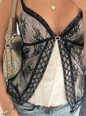 Svart spetslinnet med rosett - Snyggt svart spetslinnet med tunna axelband och dekorativ rosett framtill. Toppen har transparent spets med blommönster och en vit underdel som ger en cool kontrast. Perfekt för att skapa en trendig lager-på-lager-look.