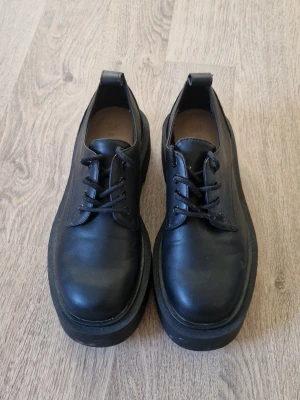 Svarta chunky loafers - Säljer ett par svarta loafers med chunky sula och snörning. Skorna är i något fejk skinn matrial. Endast använda en gång.