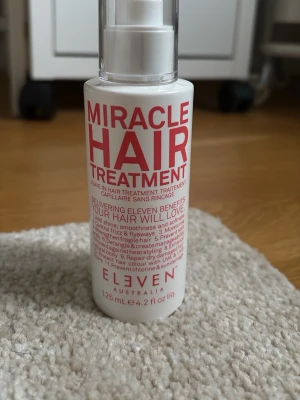 Miracle Hair Treatment Eleven Australia - Miracle Hair Treatment från Eleven Australia är en leave-in hårbehandling i en vit plastflaska med röd text. Produkten ger elva fördelar för håret, som glans, mjukhet och skydd mot värme. Flaskan har en praktisk pump och rymmer 125 ml. Den är endast testad! 