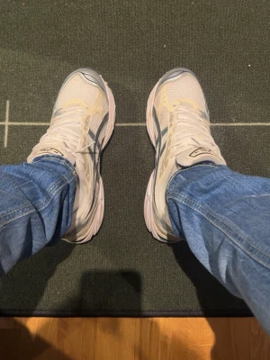 Asics nyc gel - Snygga sneakers från Asics i vitt och ljusgrått med detaljer i silver och meshmaterial. Skorna har en sportig design med tydliga Asics-loggor på sidan och tungan. Perfekta för dig som gillar retrovibbar och bekväma skor till vardags.