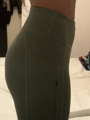 Gröna höga leggings  - Snygga gröna leggings med hög midja och markerade sömmar som framhäver formerna. Stretchigt material som sitter tight och bekvämt. Perfekta för träning eller chill. Vet ej exakt storlek men troligtvis S.