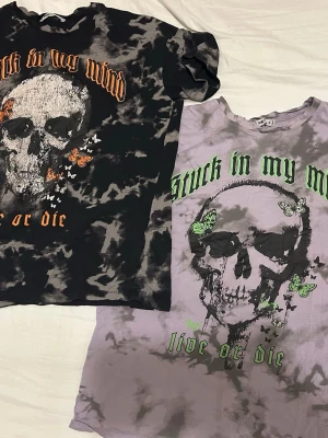 Tie dye t-shirts med dödskalletryck - Två trendiga tie dye t-shirts med stort dödskalletryck och texten 'stuck in my mind, live or die'. En är svart och grå med orange detaljer, den andra är lila och grå med gröna detaljer. Båda har korta ärmar och är i mjuk bomull. Perfekt om du tillexempel vill matcha med en vän. Storlek S men passar även mig som är M.