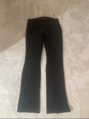 Svarta lågmidjade kostymbyxor från Bik Bok - Snygga svarta kostymbyxor från Bik Bok med klassisk rak passform och pressveck. Byxorna har hällor för skärp och stängs med dragkedja och knapp. Perfekta för en stilren look och passar till många olika outfits.