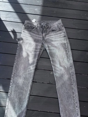 Grå Levi's 502 jeans straight fit - Säljer ett par gråa Levi's 502 jeans med rak passform och klassisk femficksdesign. Jeansen har en snygg tvättad look och är tillverkade i denim. Perfekta för dig som gillar en avslappnad men stilren vibe.