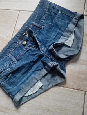 Blå vintage  y2k low waist shorts från Tally Weijl med fina spetsfickor som sticker fram - Säljer ett par blå jeansshorts från Tally Weijl, säljer då de inte passade mig, tvärsnygga och jättelowwaist, toppskick.  De har upprullade benslut, och fina fickor i vit spets. Vintage Tally Weijl. Perfekta till sommaren!  Det är bara att skriva vid eventuella frågor!💗