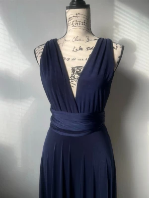 Marinblå långklänning från Goddiva - Elegant marinblå långklänning från Goddiva. Köptes av en annan säljare. Har endast använt en gång. Tidigare säljer nämnde att hen hade klippt klänningen så att den har en kortare framsidan och längre baksidan. Därför är inte längden helt jämn. Se bilder för detaljer. Man kan också se att klänningen är klippt och att den har små fläckar längst nere i klänningen som inte är så synbara. Från röda linjen jag gjort på en bild är Framsidans längs ca 112cm och baksidan är ca 124 cm. Storlek XS