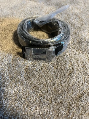 Svart skärp med silverfärgat H-spänne - Snyggt svart bälte med ett stort H-format spänne i silverfärg. Bältet har vit kontrastsöm längs kanterna och är gjort i ett material som liknar skinn. Perfekt accessoar för att lyfta din outfit. 