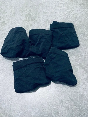 5-pack svarta stringtrosor från H&M - Säljer ett 5-pack svarta stringtrosor från H&M. Trosorna har en enkel och klassisk design med smala sidor och låg midja. Tillverkade i mjukt och stretchigt material för skön passform. Perfekta för dig som gillar minimalistisk stil.