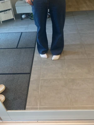 Mörkblåa vida jeans - Säljer ett par mörkblåa jeans med breda ben och hög midja. Jeansen har en klassisk femficksmodell och är tillverkade i denim. Perfekta för dig som gillar en avslappnad och trendig stil.