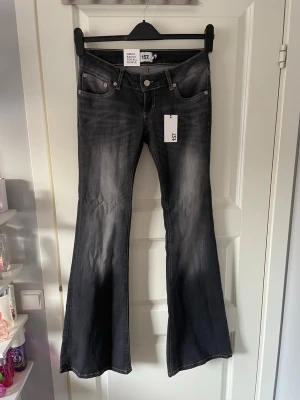 Svarta bootcut jeans från 157 - Snygga svarta bootcut jeans från 157 med slitningar och klassisk femficksmodell. Jeansen har en markerad midja, utsvängda ben och kontrastsömmar. Perfekta för dig som vill ha en trendig och avslappnad look. Materialet är bomull med stretch. Aldrig använda 