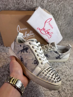 Christian Louboutin sneakers med nitar - | Skick: 9/10 | Färg: Vit, Silver, Blå och grå | Vad inkluderas: Skor, Dustbag och Box | Nypris: 12 000kr |