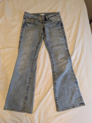 Ljusblå bootcut jeans - Säljer ett par ljusblå bootcut jeans med klassisk design. Jeansen har en lätt tvättad look och ganska låg midja. Perfekta för dig som bara behöver ett par klassiska ljusblå jeans. 