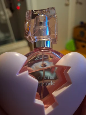 Ariana Grande Thank U Next parfym 30 ml - Ariana Grande Thank U Next parfym i en unik rosa flaska formad som ett krossat hjärta. Flaskan har en genomskinlig, kristalliknande kork och parfymen kommer i en matchande rosa förpackning. Doften är feminin och modern, perfekt för dig som gillar trendiga parfymer. 