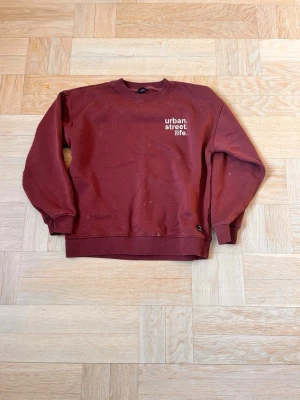 Vinröd sweatshirt 157 tröja - Vinröd sweatshirt med rund hals och trycket 'urban. street. life.' på bröstet. Tröjan har ribbade muddar vid ärmslut och nederkant. Perfekt för en avslappnad streetwear-look.