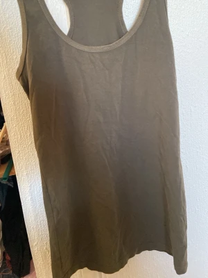 Olivgrön linnetopp från Marwin - Säljer en enkel och stilren olivgrön linnetopp från Marwin. Toppen är ärmlös med klassisk rund halsringning och har en rak passform. Perfekt att matcha med jeans eller shorts för en avslappnad look.