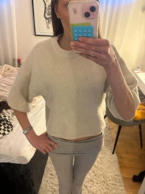 Beige stickad tröja med vida ärmar - Säljer en beige stickad tröja med rund hals och vida, trekvartsärmar. Man ser att den är tvättat men skulle inte säga att de är tecken på att den är nopprig.