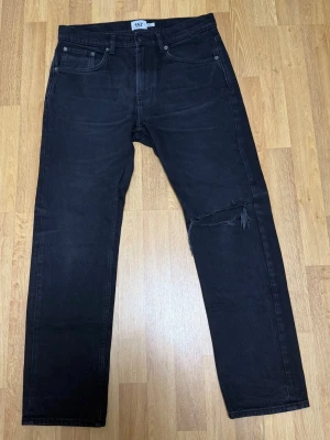 Säljer ett par 157 Black Jeans – Size W32  - Jeansen är i mycket bra skick.                               Endast använda vid något enstaka tillfälle.  Stilrena svarta jeans med washed/faded look och en diskret ripped-detalj vid knät, vilket ger en clean men ändå edgy look. Perfekta både till vardag och streetwear.  Size: W32 L30 💸 Rabatt vid köp av flera plagg!