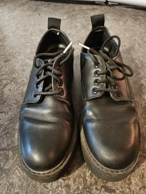 Svarta skor - Säljer ett par svarta skor från Depeche Skorna är i läder med rund tå och har en klassisk, stilren look. Perfekta för dig som gillar en edgy och tidlös stil. Passar till många olika outfits.