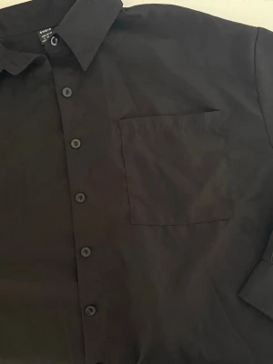 Black button-up shirt  - Black button-up shirt   Size: M Condition: used, in good condition  Details: classic black shirt with buttons, relaxed fit, easy to style, perfect basic piece  💰 Price: 80 kr  📦 Fast shipping / meet-up possible Message me if interested 💌