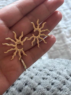 Wos örhängen - Wos örhängen i form av solar med vågiga strålar, i en snygg stål metall. Perfekta för dig som vill sticka ut och addera lite edge till din stil.