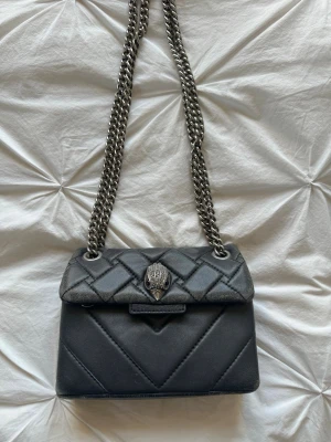 Kurt Geiger Väska  - Den har tecken på användning men inget som syns på håll! Man kan ha den både som väska tvärs över eller över ena axeln då man kan justera kedjan.