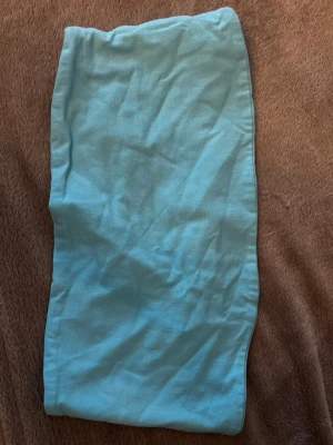 Turkos tubtopp - Enkel och snygg turkos tubsjal i mjuk bomull. Perfekt att slänga på sig för en färgklick till outfiten. Sjalen är rektangulär och har en slät yta utan mönster eller detaljer.
