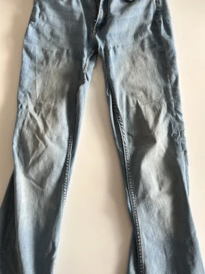 Ljusblå jeans från 157, storlek S - Ljusblå jeans från 157 i storlek S med kort längd. Klassisk femficksmodell med dragkedja och knapp. Jeansen har en rak passform och är tillverkade i bomull med lätt tvättad look och slitningar på benen.